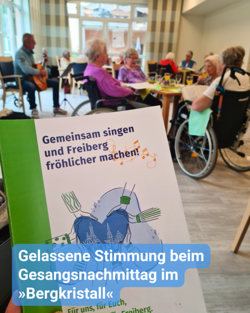 Gezeigt wird ein Gesangsheft und im Hintergrund ist eine gemütliche Runde für Senioren zu sehen. Bildbeschriftung: Gelassene Stimmung beim Gesangsnachmittag im »Bergkristall«